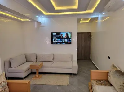 a living room with a couch and a tv on the wall at Appartement racha in Marrakech