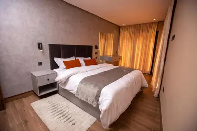 a bedroom with a large bed with white sheets and orange pillows at Élégance et Prestige à Gueliz Appartement 3 chambres in Marrakech