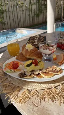 a table with a plate of food and a glass of orange juice at Villa Kenza piscine et jacuzzi chauffée in Marrakech