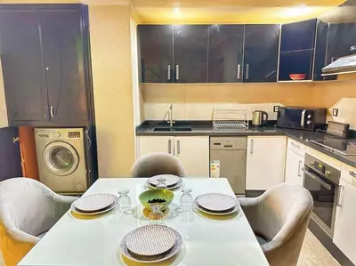 a kitchen with a white table and chairs and a kitchen with at Stylish & Comfy Appartment Haven 5 Stars Location Plaza Views in Marrakech