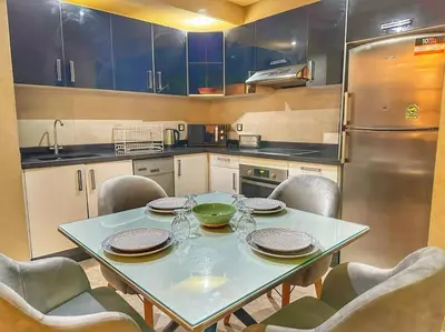 a kitchen with a table with chairs and a refrigerator at Stylish & Comfy Appartment Haven 5 Stars Location Plaza Views in Marrakech