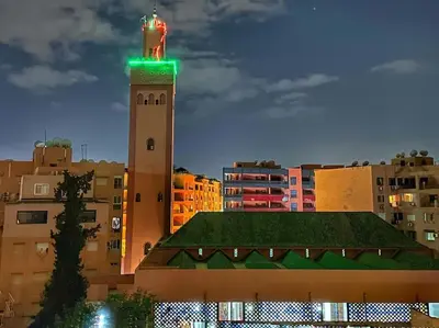 a tall tower with a green light on top of a building at Stylish & Comfy Appartment Haven 5 Stars Location Plaza Views in Marrakech