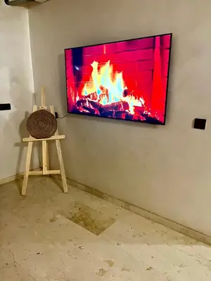 a flat screen tv hanging on a wall with a fireplace at Appartement de luxe à Marrakech in Marrakech