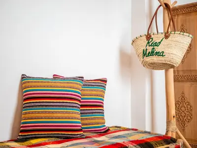 a colorful pillow sitting on a bed with a basket at Riad Melina Au Coeur de la Medina Petit Dejeuner in Marrakech