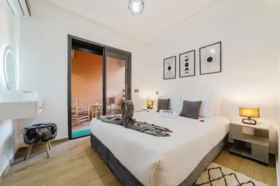 a bedroom with a large bed and a large window at Confortable & Très Bien Noté - Vue Piscine, Proche M Avenue, Piscine, Fibre Optique, Parking in Marrakech