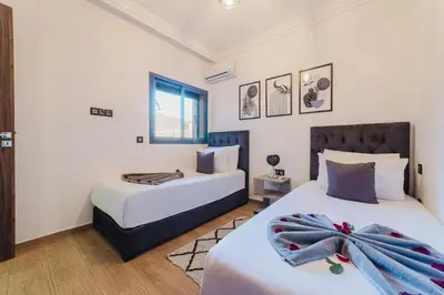 a bedroom with two beds and a window at Confortable & Très Bien Noté - Vue Piscine, Proche M Avenue, Piscine, Fibre Optique, Parking in Marrakech