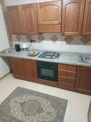 a kitchen with wooden cabinets and a stove and a rug at Luxury Apartment with swimming pool in Gueliz Marrakech in Marrakech