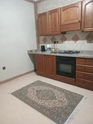 a kitchen with wooden cabinets and a rug on the floor at Luxury Apartment with swimming pool in Gueliz Marrakech in Marrakech