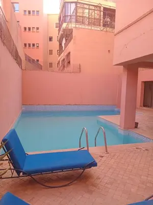 a blue pool with a chair next to a building at Luxury Apartment with swimming pool in Gueliz Marrakech in Marrakech