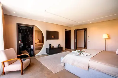 a large bedroom with a large bed and a chair at Villa Argana moderne et luxueuse piscine chauffée in Marrakech
