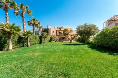 a lawn in front of a house with palm trees at Villa Argana moderne et luxueuse piscine chauffée in Marrakech