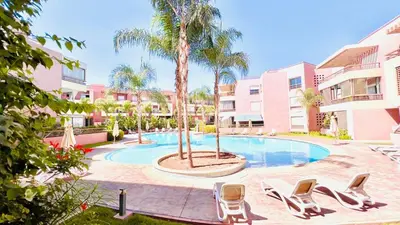 a pool with chairs and palm trees in a courtyard at Riad Garden Luxury Aparts by SABOR VOYAGE in Marrakech