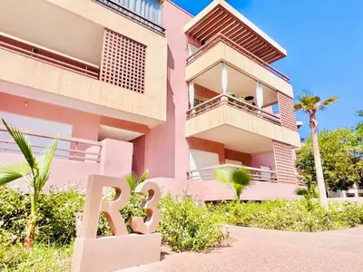 a pink building with a r sign in front of it at Riad Garden Luxury Aparts by SABOR VOYAGE in Marrakech