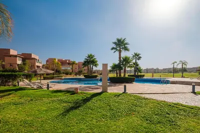 a resort with two pools and palm trees in a field at Appartement de prestige au golf in Marrakech
