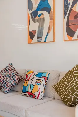 a white couch with pillows and paintings on the wall at Appartement de prestige au golf in Marrakech