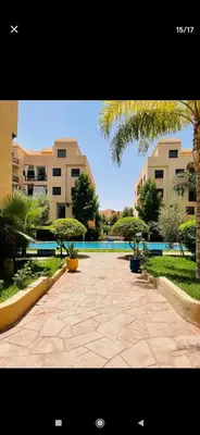 a stone walkway with palm trees and a swimming pool at Marrakesh in Marrakech