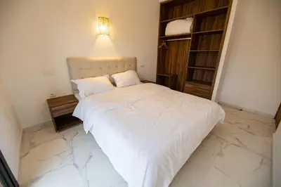a bedroom with a large white bed with a light on it at Jawhar Appart A4 in Marrakech