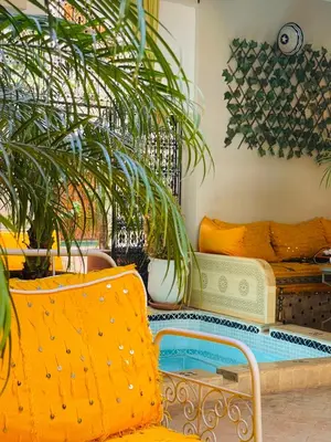 a living room with a yellow chair and a pool at Riad La Calèche in Marrakech