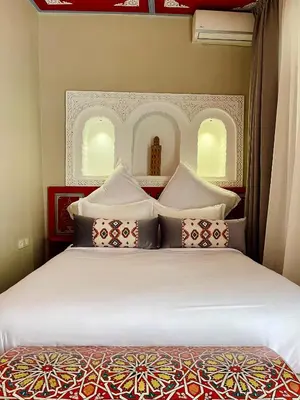 a bedroom with a bed with white sheets and pillows at Riad La Calèche in Marrakech