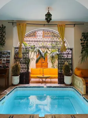 a swimming pool in a house with an open gate at Riad La Calèche in Marrakech