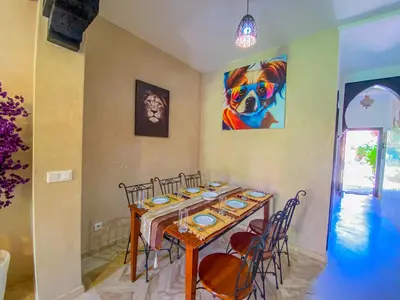 a dining room table with chairs and a painting on the wall at Hamza immobiler in Marrakech