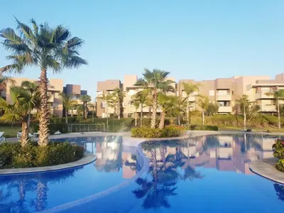 a swimming pool with palm trees and buildings in the background at Marrakech prestigia rez-de-jardin avec accès direct piscine golf in Marrakech