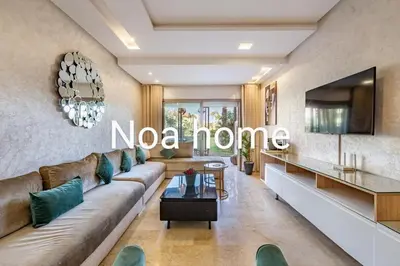a living room with a couch and a tv at Marrakech prestigia rez-de-jardin avec accès direct piscine golf in Marrakech