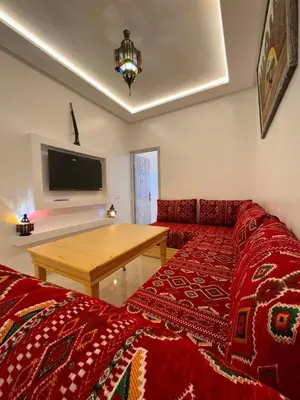 a living room with a red bed and a wooden table at Appartement Neuf et Moderne in Marrakech