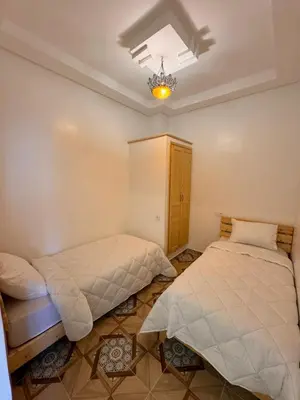 a bedroom with two beds and a chandelier at Appartement Neuf et Moderne in Marrakech
