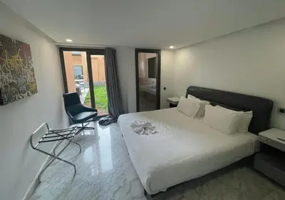 a bedroom with a white bed and a chair at Très Beau Duplexe avec piscine depuis la terrasse in Marrakech