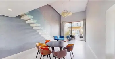 a dining room with a table and chairs and a staircase at Très Beau Duplexe avec piscine depuis la terrasse in Marrakech