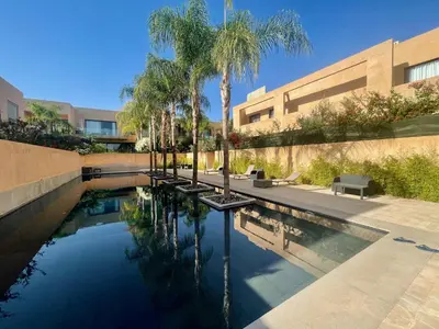 a swimming pool with palm trees in front of a building at Très Beau Duplexe avec piscine depuis la terrasse in Marrakech