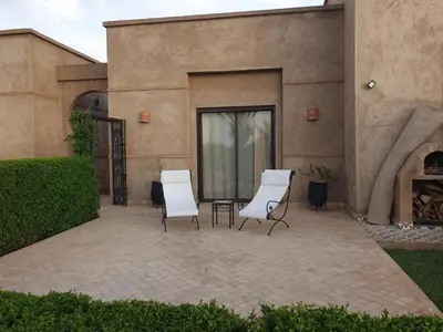 two chairs and a table in front of a building at Villa Bohème Havre de paix, piscine chauffée,4 Suites in Marrakech