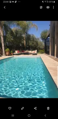 a swimming pool with blue water in front of a house at Villa Bohème Havre de paix, piscine chauffée,4 Suites in Marrakech