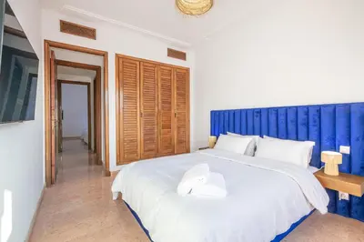 a bedroom with a large white bed with a blue headboard at Appartement cosy Piscine et chill in Marrakech