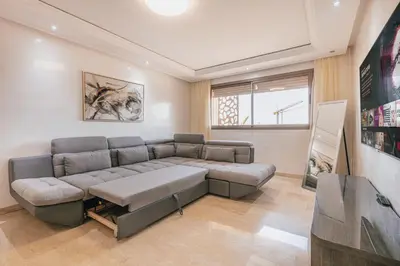 a living room with a couch and a tv at Migdal Gueliz Apart Hôtel in Marrakech