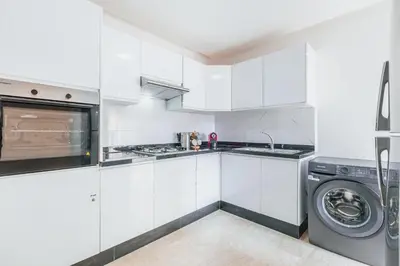 a kitchen with white cabinets and a washer and dryer at Migdal Gueliz Apart Hôtel in Marrakech