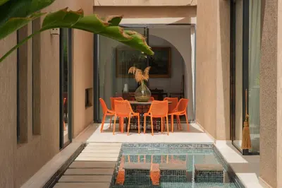 a dining room with a table and chairs next to a pool at Villa Netumia in Marrakech