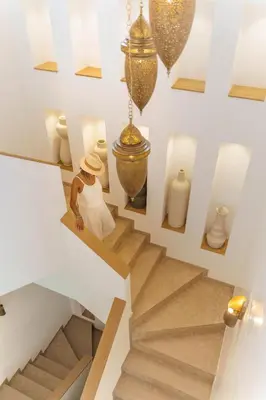 a woman is walking down a staircase with vases at Villa Eyline Amelkis Golf in Marrakech