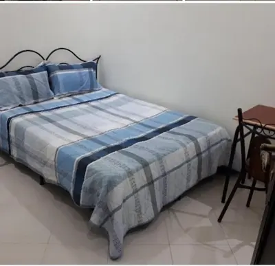 a bed with a blue and white comforter in a room at Maison D'hôte Dar ALBIDAWI in Marrakech