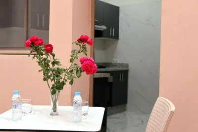 a vase with red flowers on a table with water bottles at Majestic luxe appartment in Marrakech