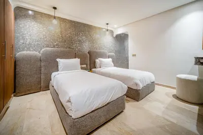 a bedroom with two beds and a wall at Kasbel 2 Appart & Pool in Marrakech