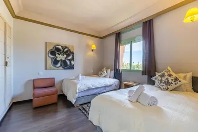 a hotel room with two beds and a chair at Best location new appart hivernag Pool FreeParking in Marrakech