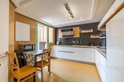 a kitchen with white cabinets and a table and chairs at Best location new appart hivernag Pool FreeParking in Marrakech