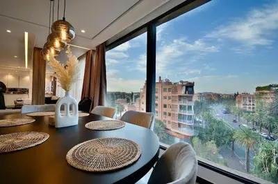 a dining room with a table and a large window at Appartement De Luxe à Marrakech avec jacuzzi piscine et vue panoramique in Marrakech