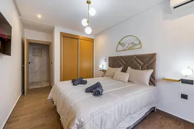 a bedroom with a large white bed with two bags on it at Family appartment Palmeraie Gate with pool in Marrakech