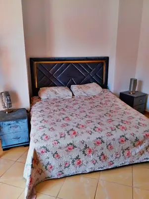 a bedroom with a bed with a floral comforter at Appartement calme et spacieux in Marrakech