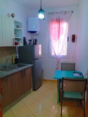 a kitchen with a refrigerator and a table and a window at Appartement calme et spacieux in Marrakech