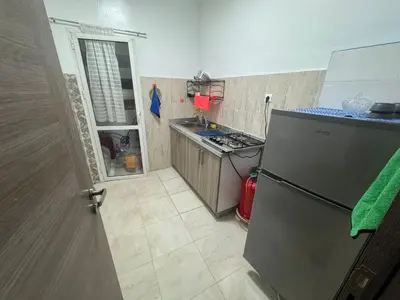 a small kitchen with a refrigerator and a sink at Joli appartement nouveau Rez-de-chaussée in Marrakech