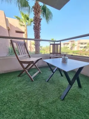a table and a chair sitting on a patio at Appartement Central, vue Piscine-Golf, Lac et Montagne de L'atlas in Marrakech